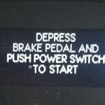 Надпись DEPRESS BRAKE PEDAL AND PUSH POWER SWITCH TO START